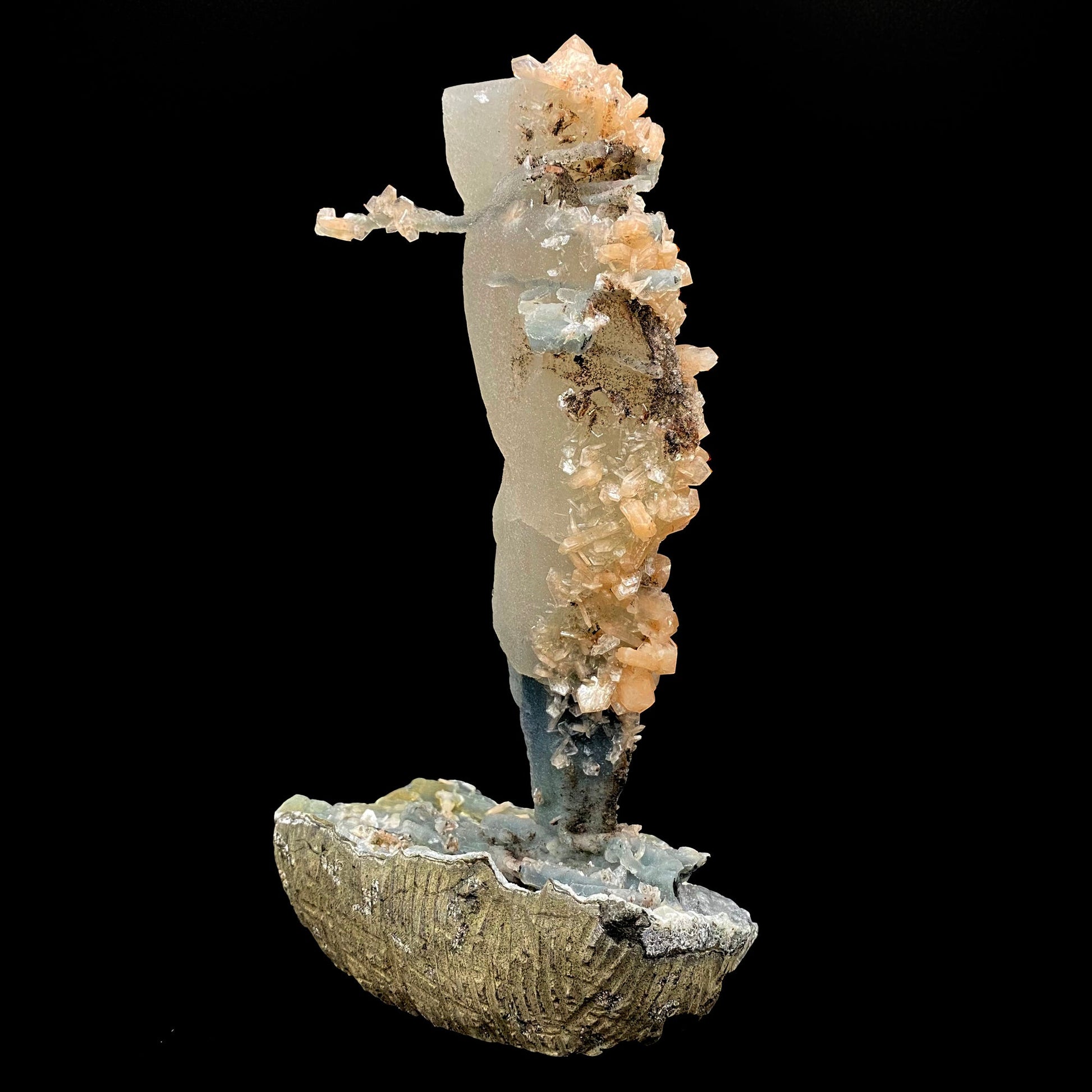 Towering calcite specimen coated in chalcedony and stilbite with a single distinctive, delicate stalactite growing sideways near the top termination, with stilbite blades of its own. The base is blue chalcedony stalactites with basalt on the bottom.