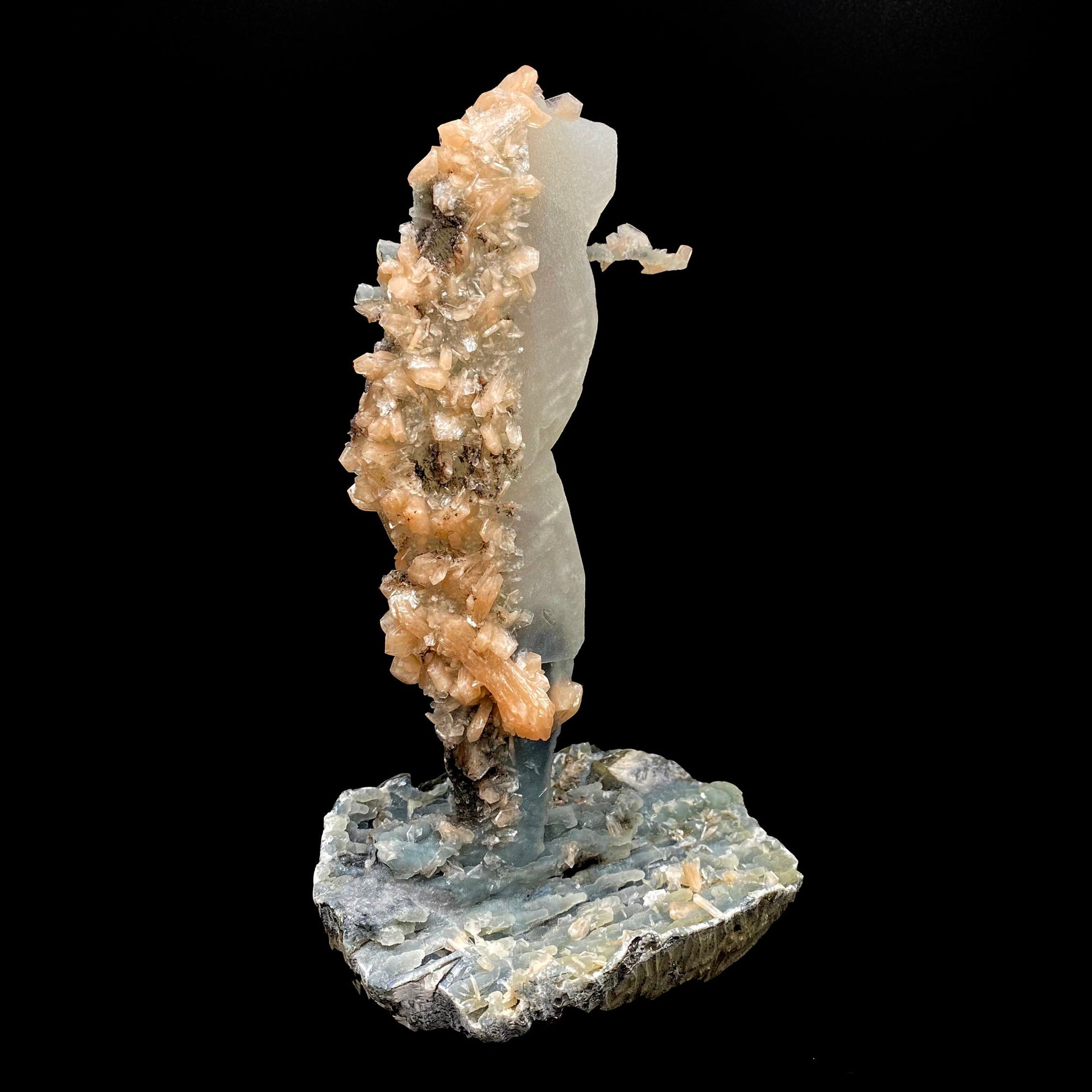 Towering calcite specimen coated in chalcedony and stilbite with a single distinctive, delicate stalactite growing sideways near the top termination, with stilbite blades of its own. The base is blue chalcedony stalactites with basalt on the bottom.